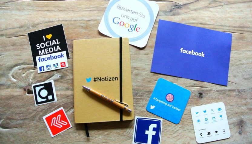 a note book and some icons of social media on the wooden table